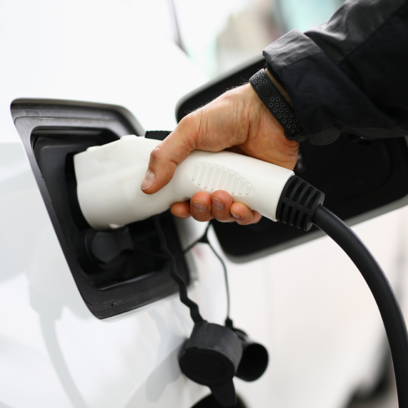 Ręka podłącza wtyczkę do ładowania samochodu elektrycznego